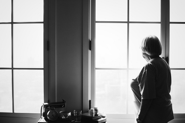 Mujer mayor ante una ventana en contraluz